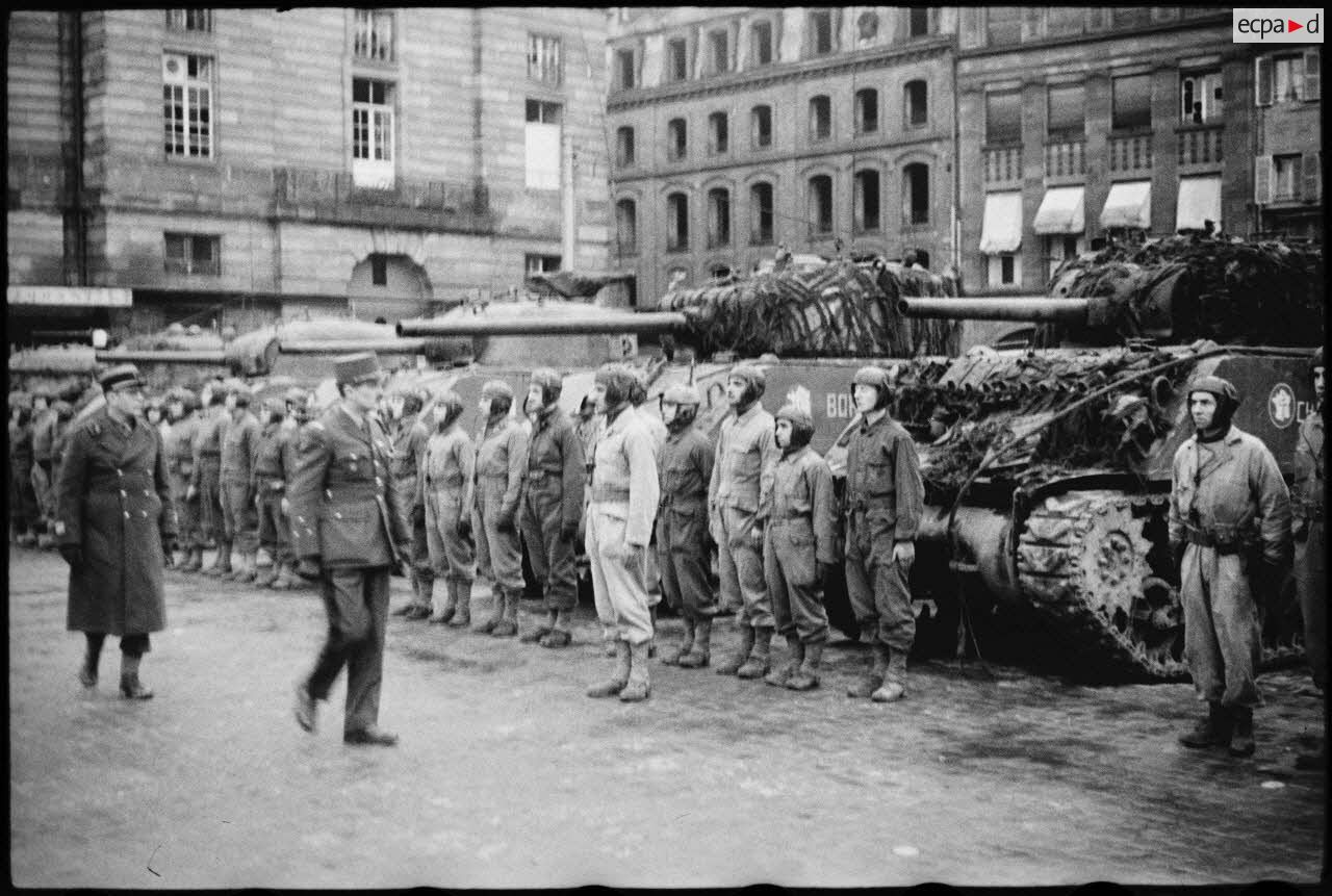 Place Kléber à Strasbourg, lors d'une cérémonie célébrant la libération de la capitale de l'Alsace par la 2e DB (division blindée), le général Leclerc, commandant la 2e DB, suivi du colonel Rouvillois, commandant le 12e régiment de cuirassiers, passe en revue les chars du 4e escadron du 12e RCA (régiment de chasseurs d'Afrique).