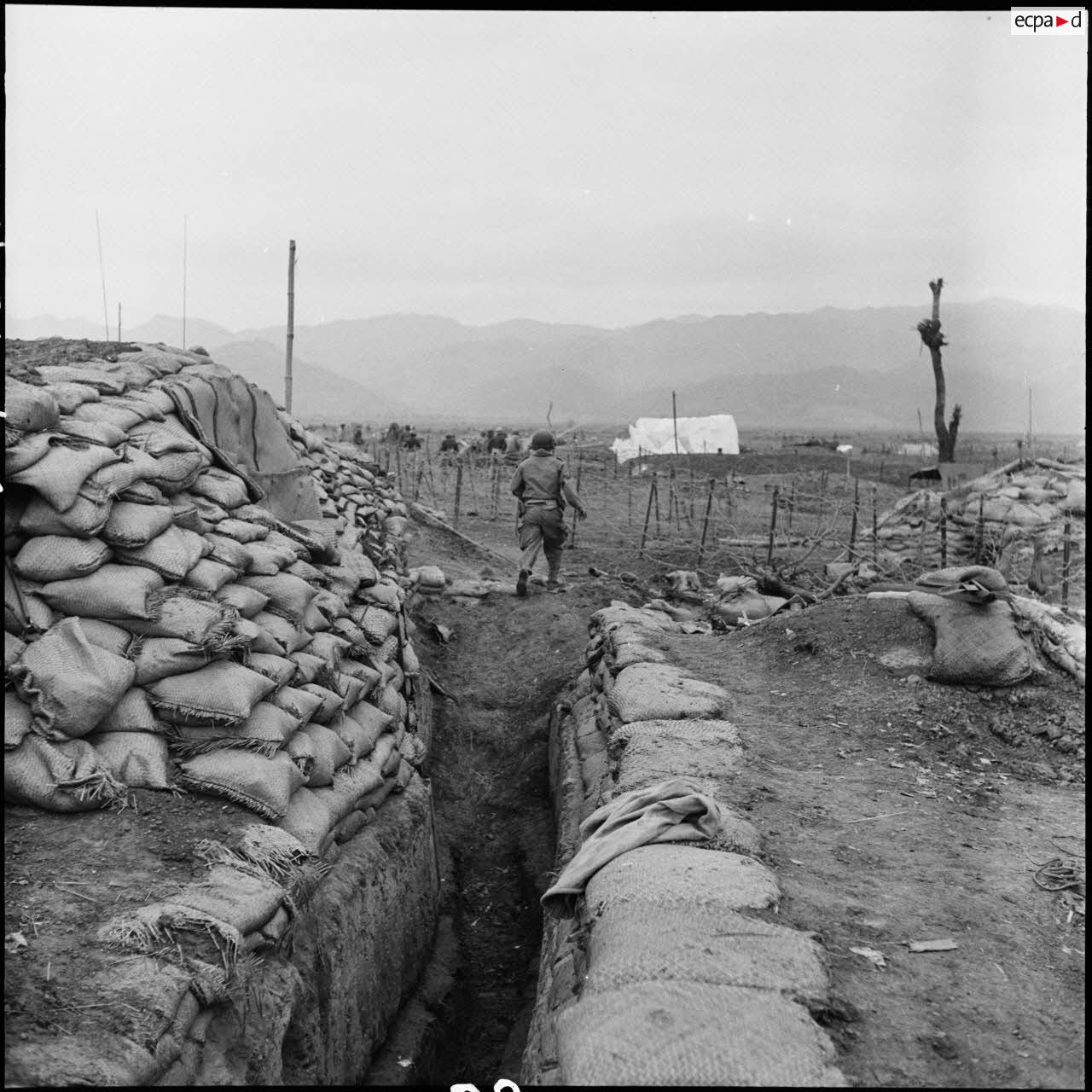 Soldat sortant d'une tranchée protégée de sacs à terre, sur le camp retranché de Diên Biên Phu.