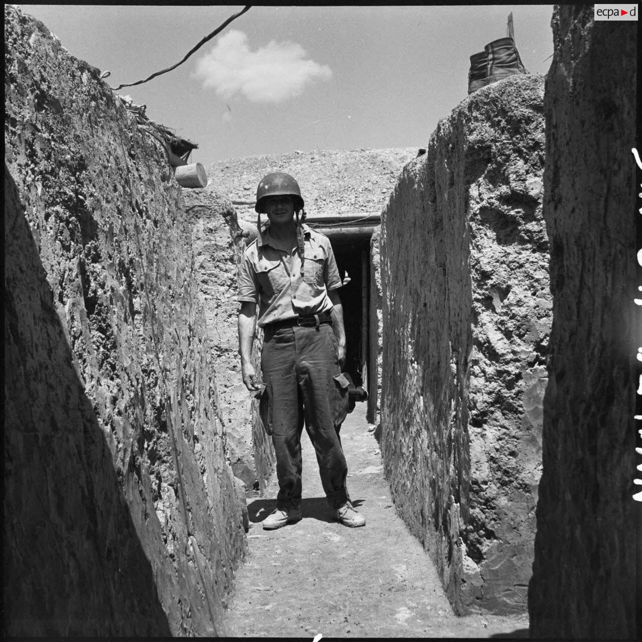 Portrait du caporal-chef Pierre Schoendoerffer, caméraman du Service cinématographique des armées, dans une tranchée de Diên Biên Phu.