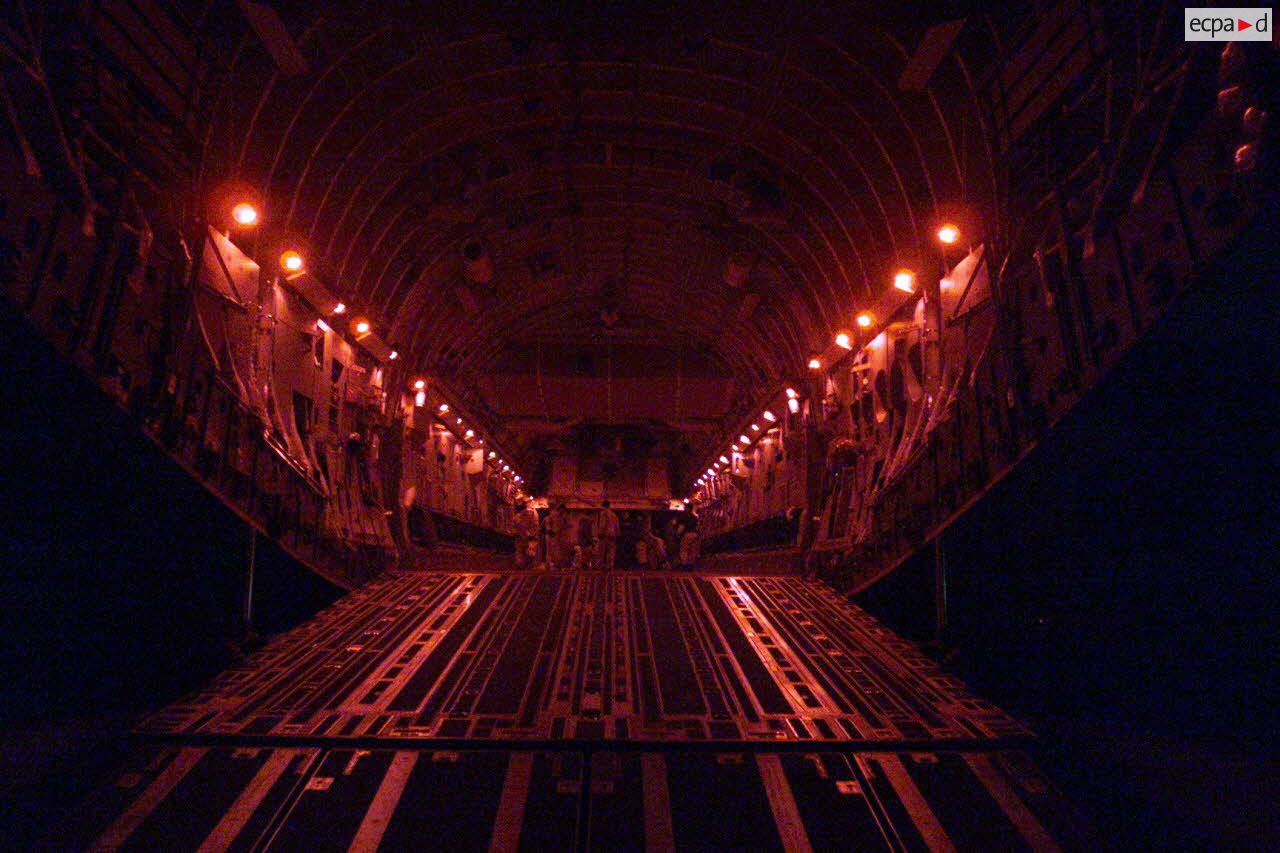 Désengagement des derniers véhicules du détachement français à l'aéroport de Mazar e Charif par avion de transport américain C-17 Globemaster. Intérieur de la soute avec l'équipage sous lumière tamisée.