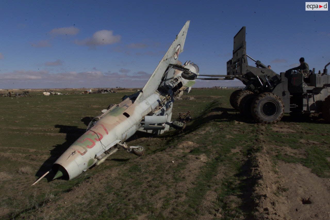 Pour préparer l'installation d'un nouveau camp, les démineurs américains poussent les épaves des anciens avions de combat MIG de l'armée soviétique à l'aide d'un engin du génie en dehors de la piste de l'aéroport de Mazar e Charif.