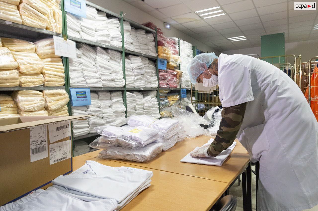 Un soldat apporte son aide pour le pliage du linge médical à l'hôpital Sainte-Anne.