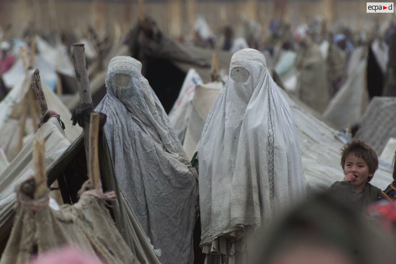 Camp de réfugiés afghans à Mazar e Charif. Portrait de femmes voilées dans le dénuement du camp.