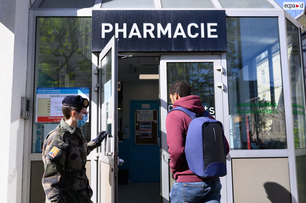 Un soldat du 24e régiment d'infanterie (24e RI) ouvre la porte à un patient à l'entrée de la pharmacie de l'hôpital de la Pitié Salpêtrière à Paris.