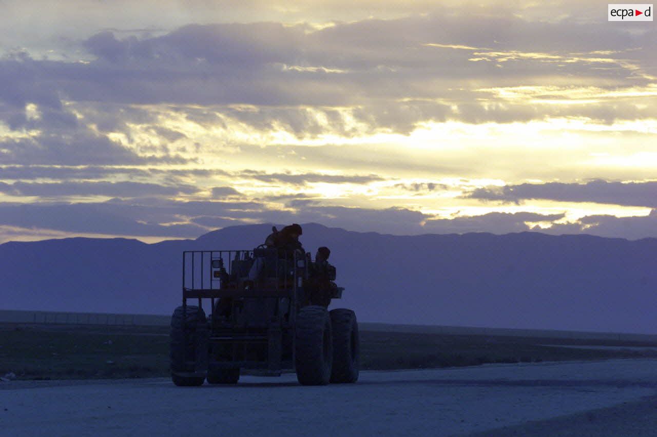 Coucher du soleil sur la piste de l'aéroport de Mazar e Charif, sur laquelle progresse un engin de manutention transpalettes.