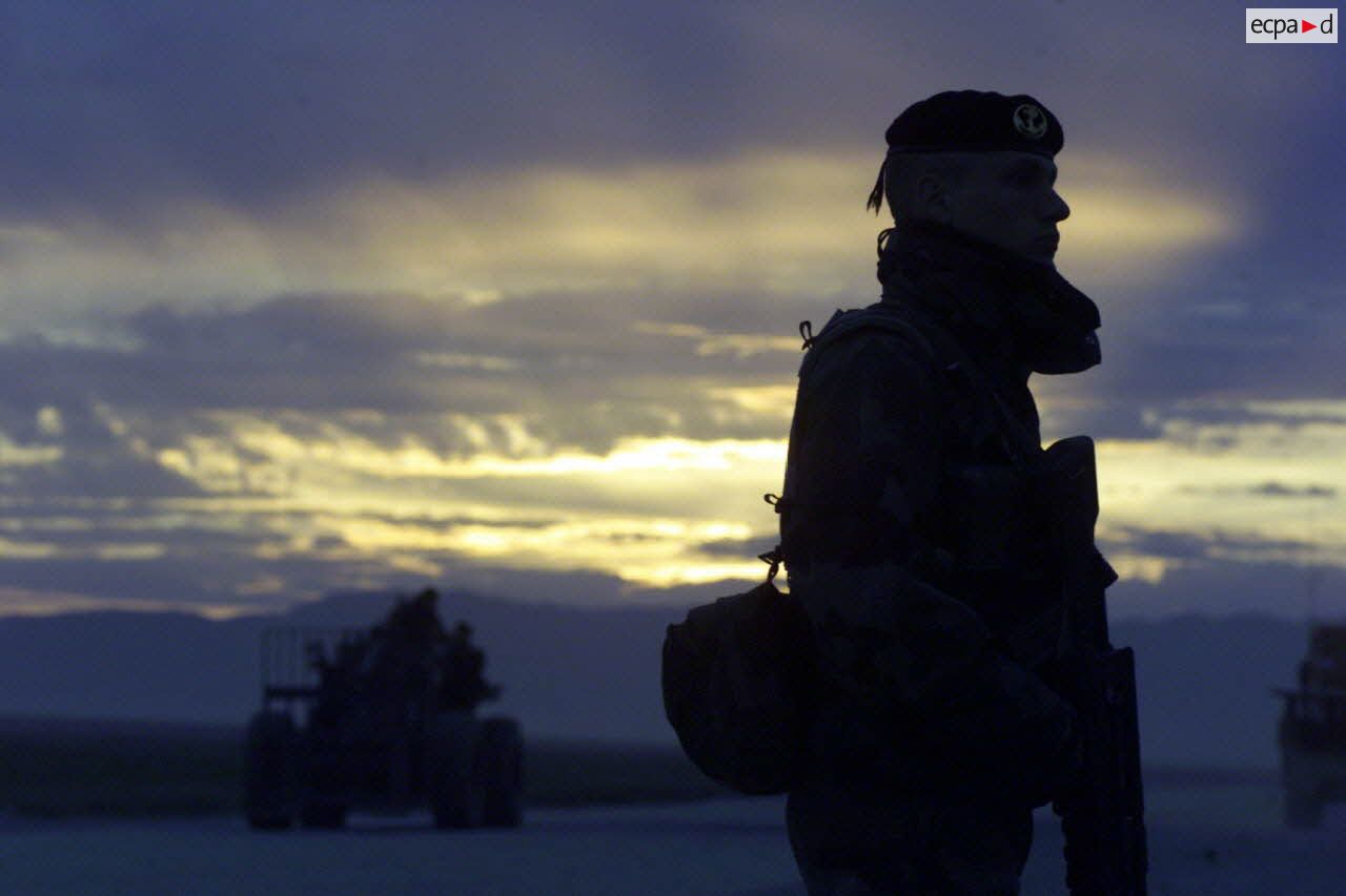 Coucher du soleil sur la piste de l'aéroport de Mazar e Charif, sécurisée par un marsouin du 21e RIMa (régiment d'infanterie de marine), et sur laquelle progresse un engin de manutention transpalettes.