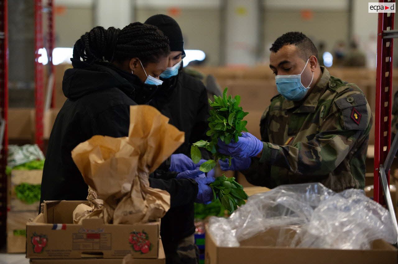 Des éléments du 2e régiment du service militaire volontaire (2e RSMV) préparent des colis de livraison alimentaires au sein d'un entrepôt du marché d'intérêt national de Rungis.