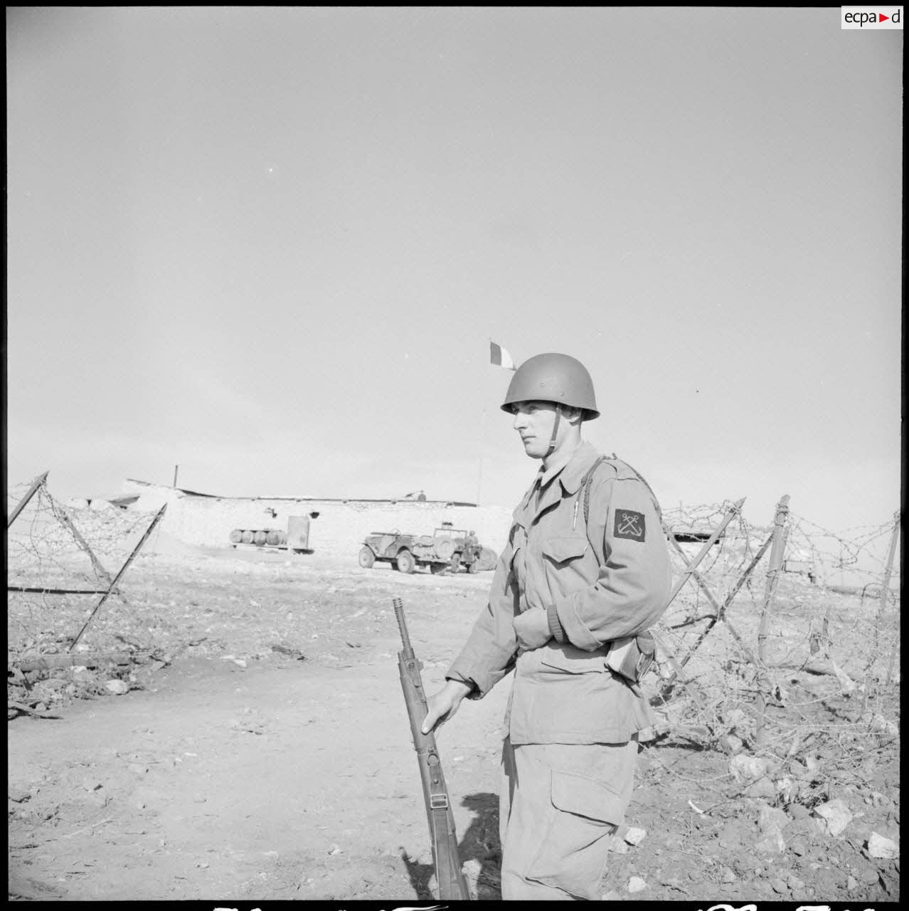 Portrait d'un fusilier-marin montant la garde avec son fusil devant un poste à la frontière algéro-marocaine.