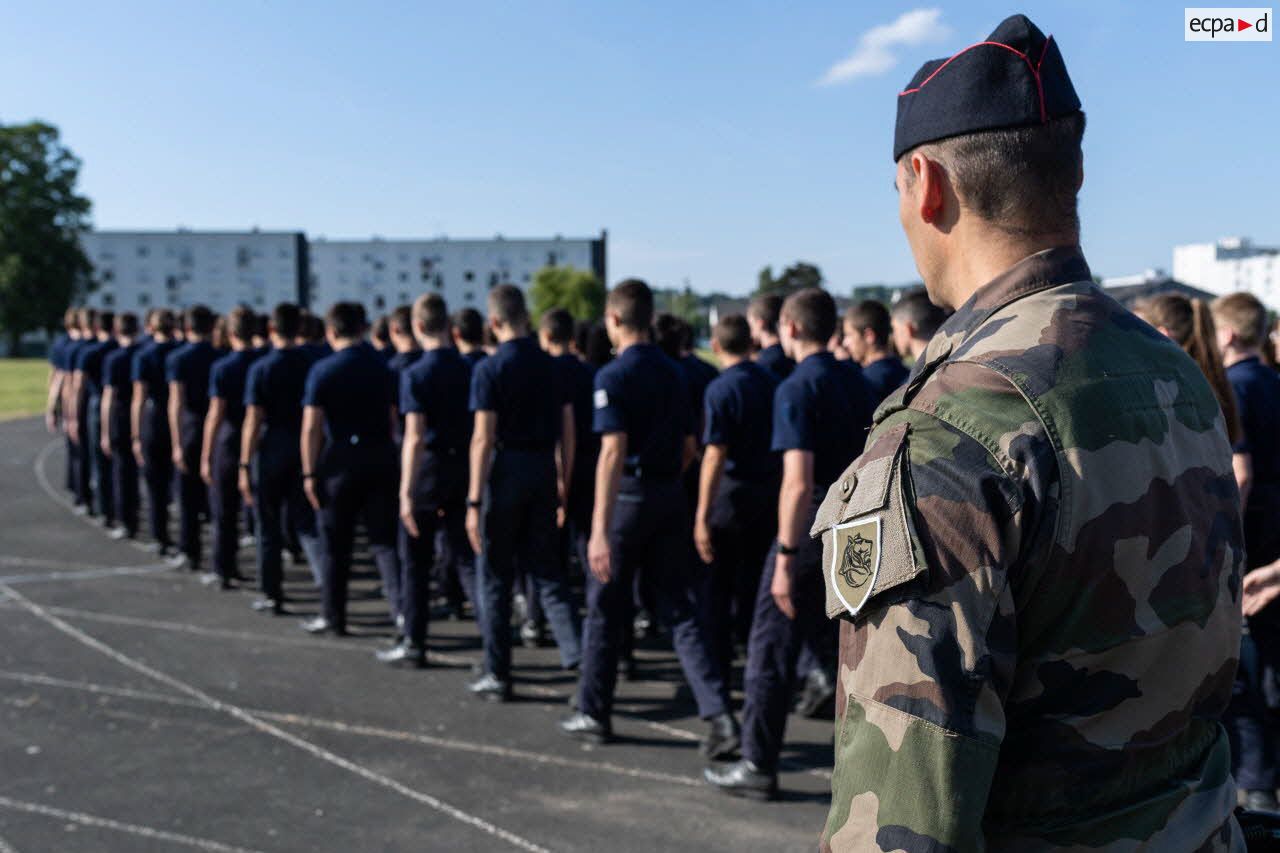 Des élèves marchent en ordre serré sous le regard d'un cadre au Prytanée National Militaire de La Flèche.