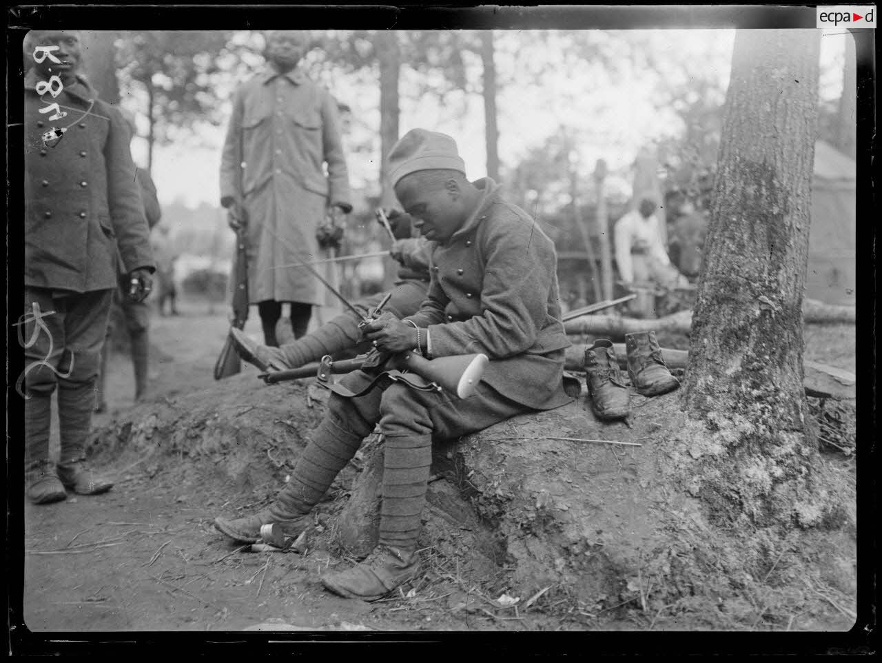 Bois d'Houssoy, près de Remaugis (Somme). Camp de tirailleurs sénégalais, 62e bataillon, Sénégalais nettoyant leurs fusils. [légende d'origine]