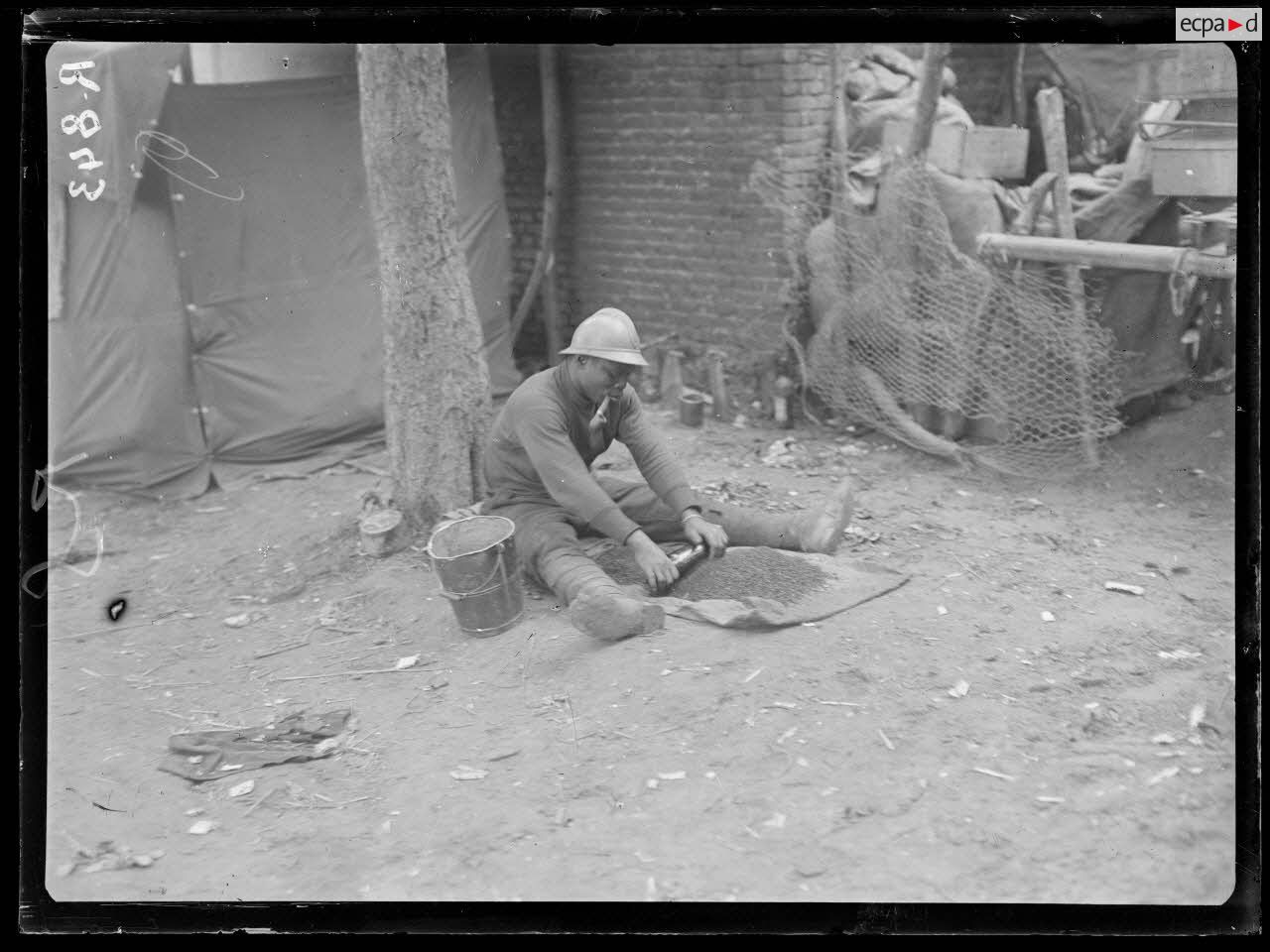 Bois d'Houssoy, près de Remaugis (Somme). Camp de tirailleurs sénégalais, 62e bataillon, soldat écrasant du café. [légende d'origine]