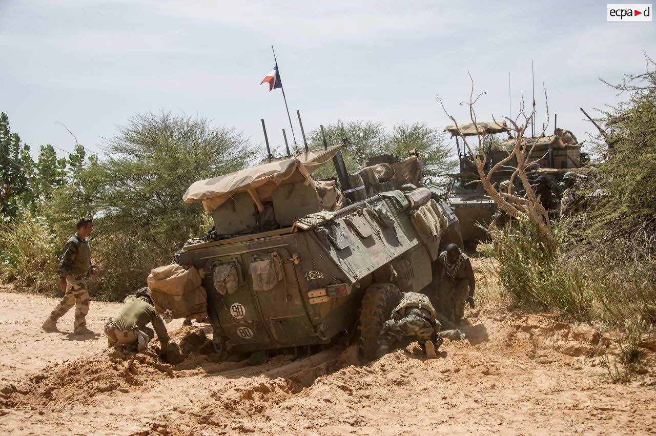 Des soldats des forces armées maliennes (FAMa) dégagent un véhicule de l’avant blindé (VAB) ensablé dans un oued lors du franchissement du fleuve Niger.