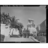 Plan en contre-plongée d'autorités civiles et militaires qui descendent les marches du monument aux morts d'Alger.