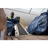 Les colis sont déchargés de l'avion-cargo Boeing 777F d'Air-France KLM par le personnel de l'aéroport de Bangui M'Poko, utilisant un engin convoyeur élévateur Tug.