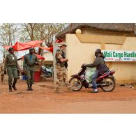 Militaire assurant la sécurité des abords du bâtiment du PC (poste de commandement) de la 3e BM (brigade mécanisée), à côté de l'aéroport international de Bamako (Mali). Contrôle d'identité d'un passant en moto.