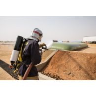 Un pompier de l'Air éteint un feu déclaré sur un bac souple carburant du Service des essences des armées (SEA) au moyen d'une lance incendie sur la base aérienne de Niamey, au Niger.