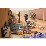 Des soldats achètent des articles sur un marché établi devant l'entrée de la zone vie du détachement Air de la base aérienne de Niamey, au Niger.