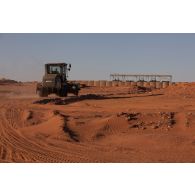 Une niveleuse terrasse le sol autour de la base avancée temporaire (BAT) de Madama, au Niger.