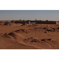 Un chariot élévateur lourd (CEL) et un chariot téléscopique MLT 940 terrassent le sol autour du dépôt du Service des essences (SEA) de la base avancée temporaire de Madama, au Niger.