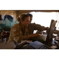 Le maréchal des logis Margaux et le brigadier-chef Christian paramètrent une valise satellitaire broaddbang global area network (BGAN) au poste de commandement tactique (PCTAC) de Madama, au Niger.