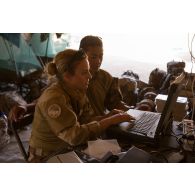 Le maréchal des logis Margaux et le brigadier-chef Christian paramètrent une valise satellitaire broaddbang global area network (BGAN) au poste de commandement tactique (PCTAC) de Madama, au Niger.