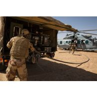 Des soldats du Service des essences des armées (SEA) avitaillent un hélicoptère Caracal EC-725 en carburant depuis leur camion-citerne CBH-385 sur la piste de Madama, au Niger.