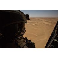 Un membre opérationnel de soute (MOS) sécurise le vol d'un hélicoptère Caracal EC-725 au-dessus de la piste de Madama, au Niger.