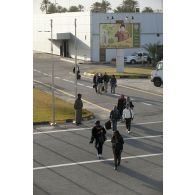 Des ressortissants évacués se dirigent vers leur avion pour l'embarquement sur l'aéroport de Tripoli (Libye), passant près d'une affiche représentant le colonel Kadhafi.