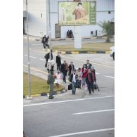 Des ressortissants évacués se dirigent vers leur avion pour l'embarquement sur l'aéroport de Tripoli (Libye), passant près d'une affiche représentant le colonel Kadhafi.