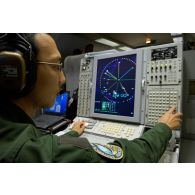 Portrait d'un sergent opérateur d'ESM (electronic support measure ou système d'écoute d'émissions) devant son écran radar, lors d'une mission de contrôle aérien sur la Libye à bord d'un avion de détection Awacs.