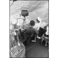 Marins à leur poste d'observation sur la passerelle extérieure d'un des bâtiments du convoi. A gauche, une lanterne Scott et une alidade de navigation.