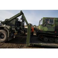 Un soldat guide le chargement d'un véhicule articulé chenillé (VAC) Bandvagn 206 à bord d'un camion porteur polyvalent logistique (PPLOG) à Jõhvi, en Estonie.