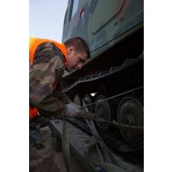 Un soldat fixe les chenilles d'un véhicule articulé chenillé (VAC) Bandvagn 206 à la plateforme d'un camion porteur polyvalent logistique (PPLOG) à Jõhvi, en Estonie.