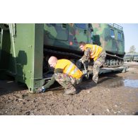 Des soldats fixent les chenilles d'un véhicule articulé chenillé (VAC) Bandvagn 206 à la plateforme d'un camion porteur polyvalent logistique (PPLOG) à Jõhvi, en Estonie.