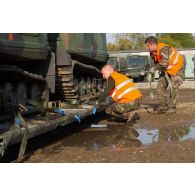 Des soldats fixent les chenilles d'un véhicule articulé chenillé (VAC) Bandvagn 206 à la plateforme d'un camion porteur polyvalent logistique (PPLOG) à Jõhvi, en Estonie.