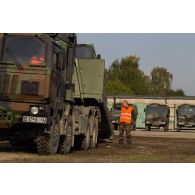 Un soldat encadre le chargement d'un véhicule articulé chenillé (VAC) Bandvagn 206 à bord d'un camion porteur polyvalent logistique (PPLOG) à Jõhvi, en Estonie.