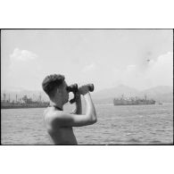 Marin observant les navires de transport dans le Golfe de Saint-Tropez. A l'arrière-plan, à gauche, un Liberty ship et à droite, un Fort ship (Canada).