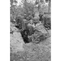 Les casques recouverts d'une moustiquaire, des fantassins de l'armée de l'air allemande dans un tranchée, parmi eux un photographe équipé d'un Leica III.