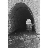 Traversée d'un tunnel par un sous-officier allemand armé d'un pistolet-mitrailleur MP-40.