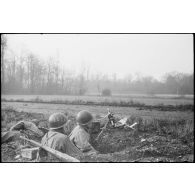 Dans le secteur de Benfeld et Wintternheim (Bas-Rhin), des fantassins, équipés d'une mitrailleuse de 30 mm, guettent à la lisière d'un bois, terrés dans un trou.