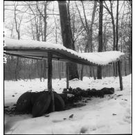 Plan moyen d'un abri rudimentaire couvert de neige où sont entreposées ce qui semble être des mines antichars.