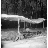 Plan moyen d'un abri rudimentaire couvert de neige où sont entreposées ce qui semble être des mines antichars.