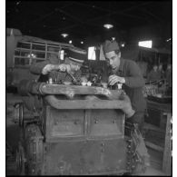 Un capitaine et un mécanicien travaillent sur un moteur dans l'atelier de réparation de campagne.