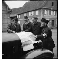 Photographie de groupe d'aumôniers militaires de confessions différentes qui regardent une carte étalée.