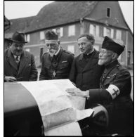 Photographie de groupe d'aumôniers militaires de confessions différentes qui regardent une carte étalée.