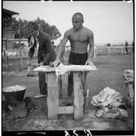 Un homme torse nu lave du linge.