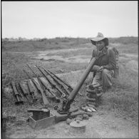 Un tirailleur laotien surveille le matériel pris au Viêt-minh.