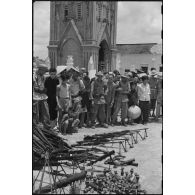 Les armes récupérées à l'ennemi sont exposées en faisceau sur la place de l'église de Ke Sat.