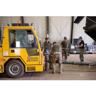 Des soldats britanniques arriment un hélicoptère Chinook Ch-47 à un tracteur d'avion pour sa sortie de hangar à Gao, au Mali.