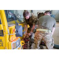 Des soldats britanniques arriment un hélicoptère Chinook Ch-47 à un tracteur d'avion pour sa sortie de hangar à Gao, au Mali.